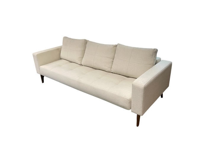 Magpie Reclamations mid-century modern sofa in cream textured fabric with tufted cushions and tapered wooden legs.